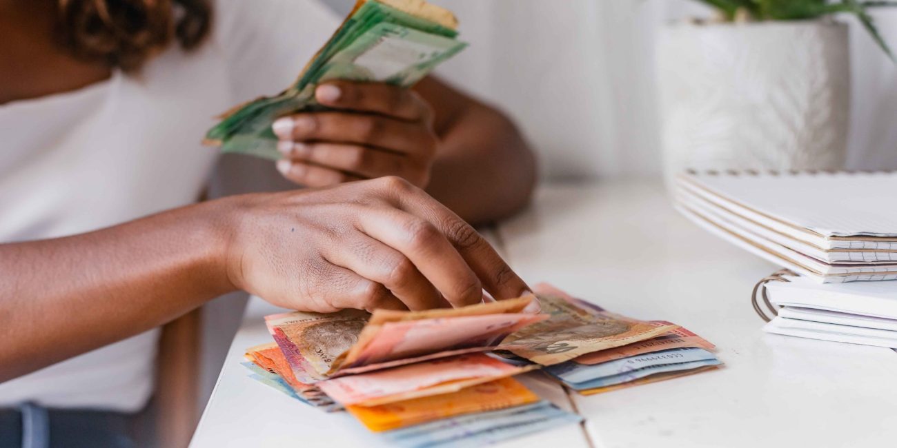 Woman counting South African rands on a white table