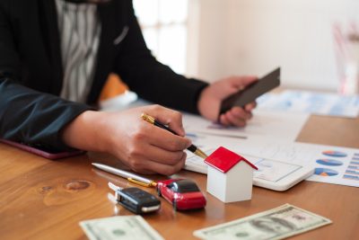 person at table with car keys, car, and house models