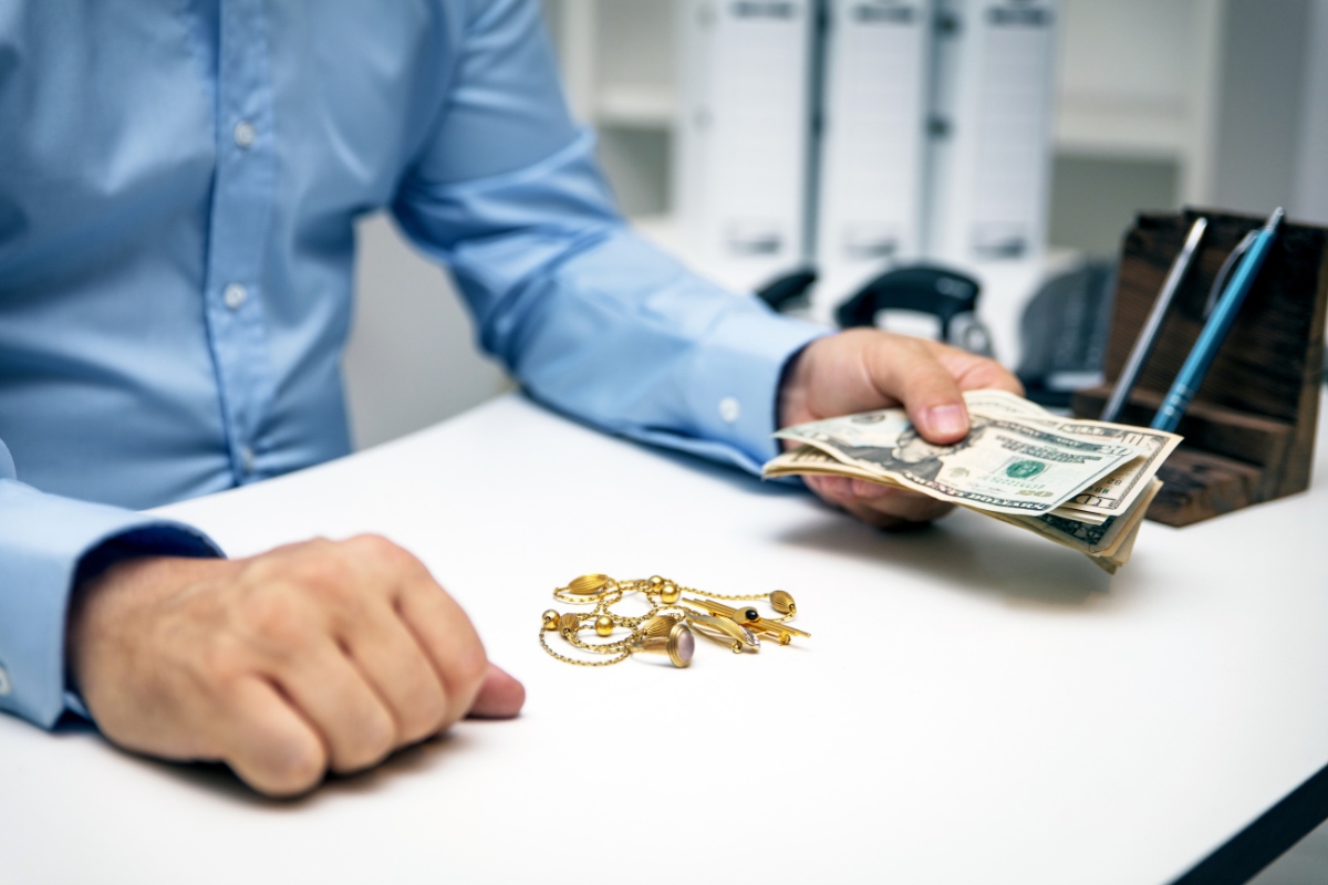 Man holding money with jewelry on table