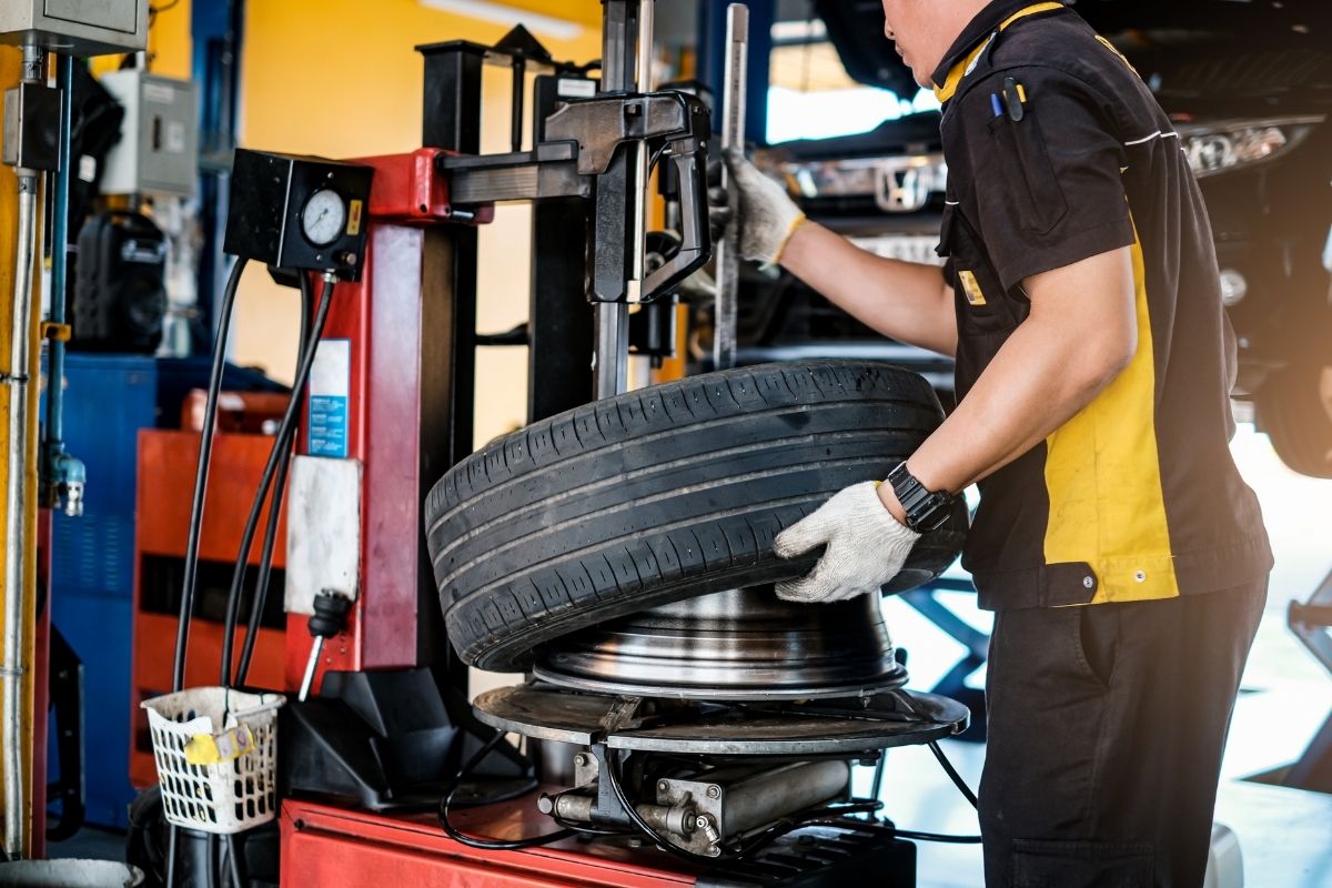 Man with gloves working with car tyre