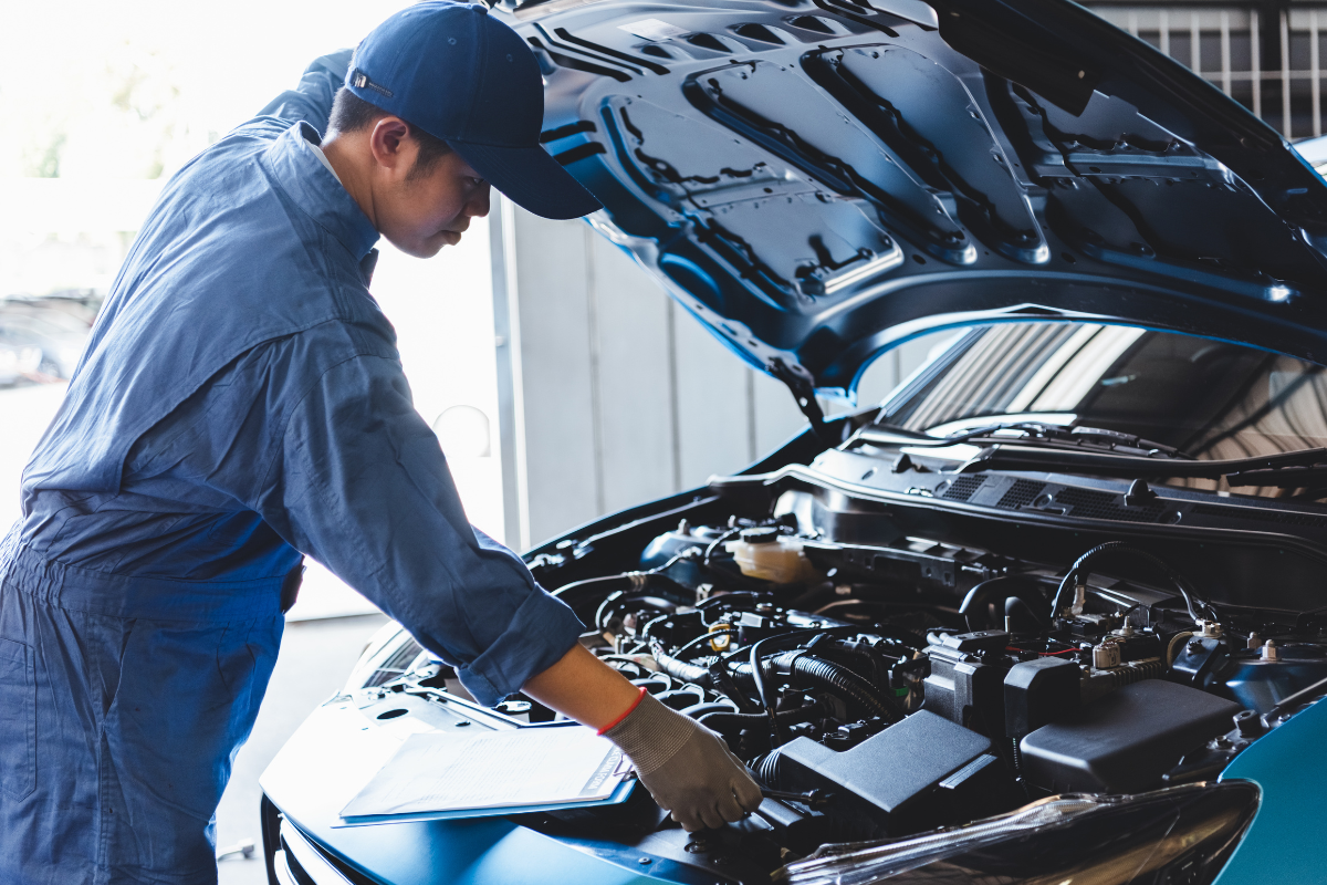 man with checkboard checking under the hood of a car